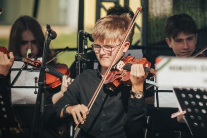 Genç müzisyenlerden oluşan orkestra sahnede keman çalıyor