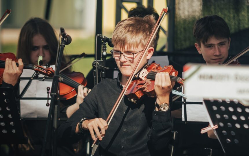 Genç müzisyenlerden oluşan orkestra sahnede keman çalıyor